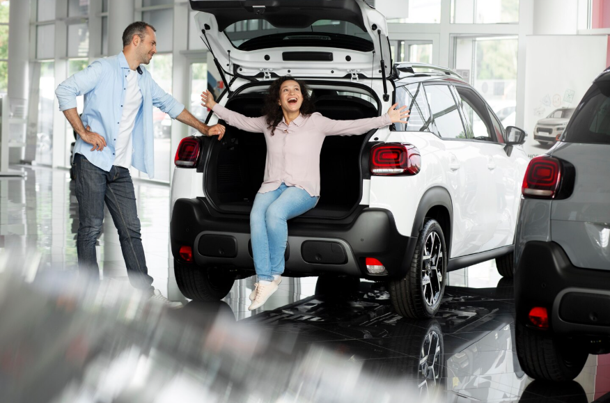 Buyers exploring a new SUV with spacious cargo area at a modern car showroom.