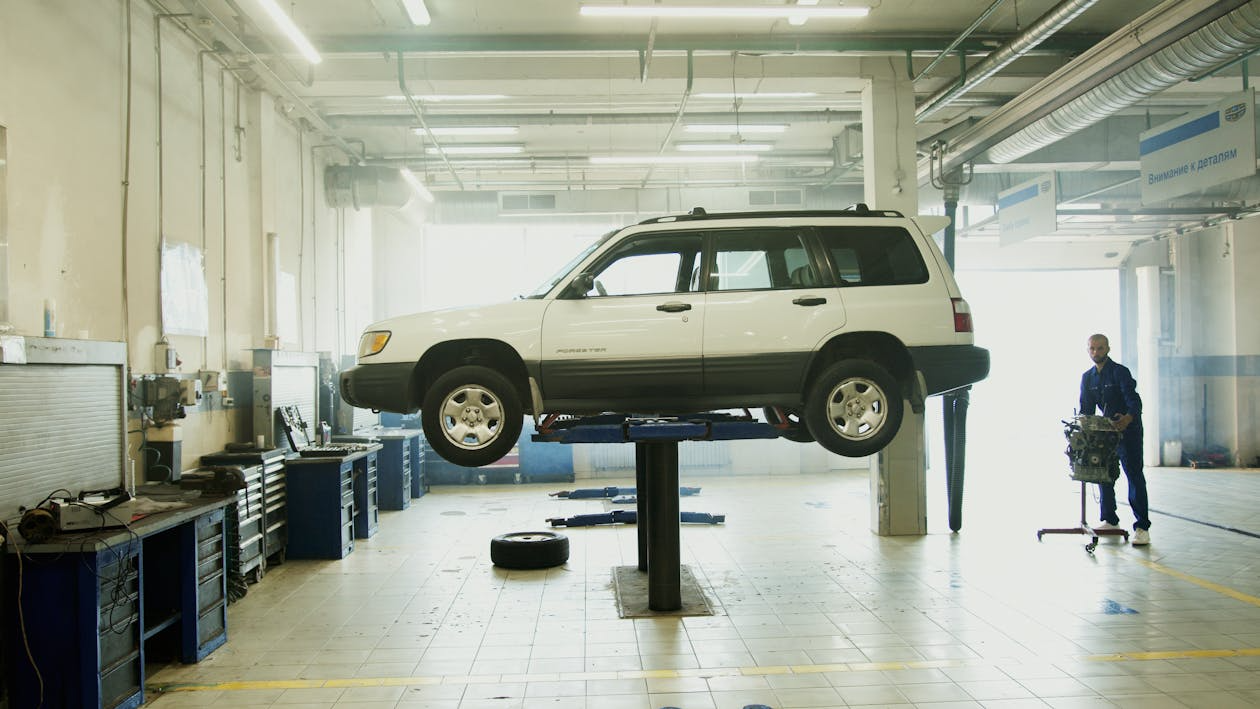 Older SUV on a lift at repair shop showing rising repair costs.